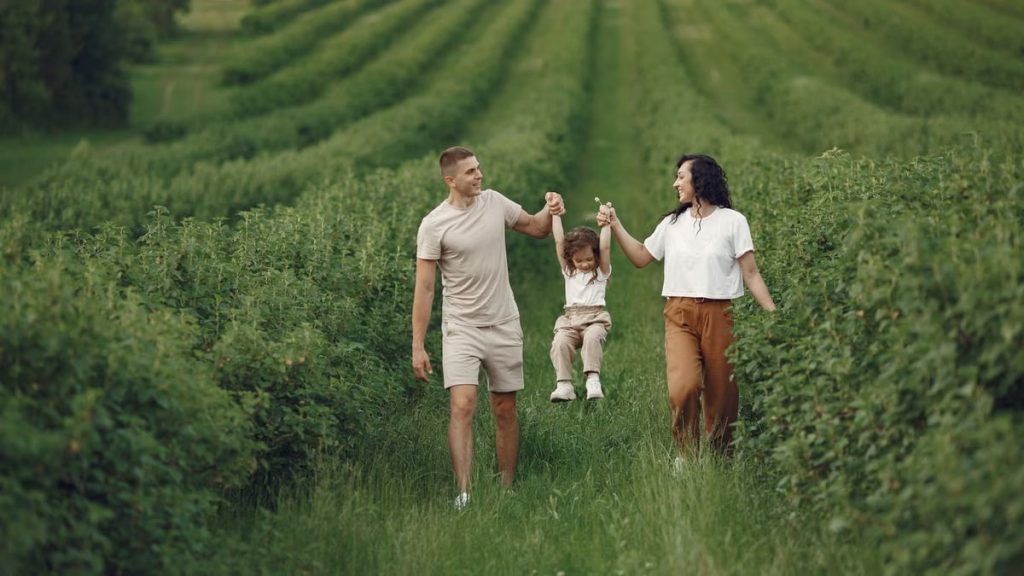 A happy family walking in a lush, green rural field together.