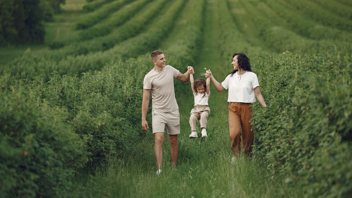 A happy family walking in a lush, green rural field together.